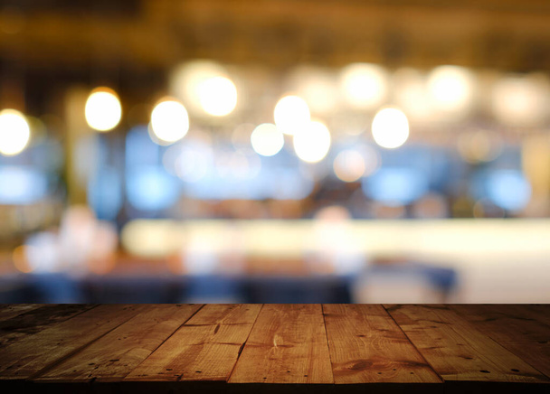 Leere Platte eines Holztisches mit abstraktem Hintergrund von verschwommenem Café-Restaurant, Café mit Bokeh-Licht Hintergrund. - kann zur Darstellung Ihrer Produkte verwendet werden. - Foto, Bild
