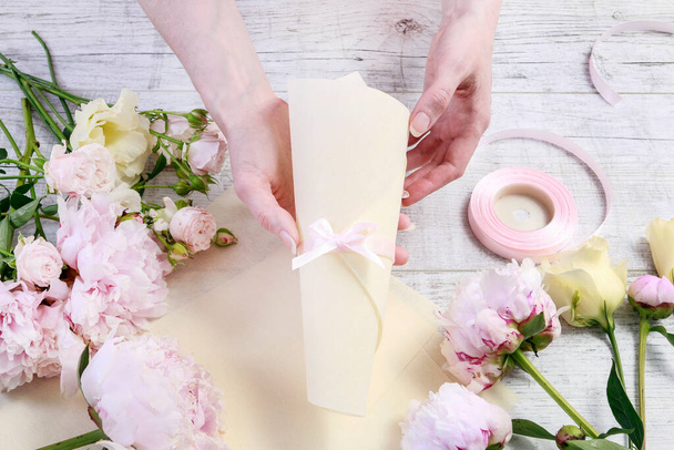 Florist at work: woman shows who to arrange flowers inside a paper cornet. Step by step, tutorial. - Valokuva, kuva