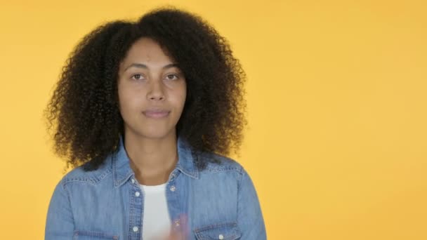 Νεαρή Αφρικανή γυναίκα που δείχνει το προϊόν, Κίτρινο φόντο  - Πλάνα, βίντεο