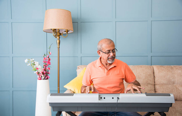 Старший азиатский индийский музыкант выступает во время занятий онлайн-музыкой или записи видео на смартфон - Фото, изображение