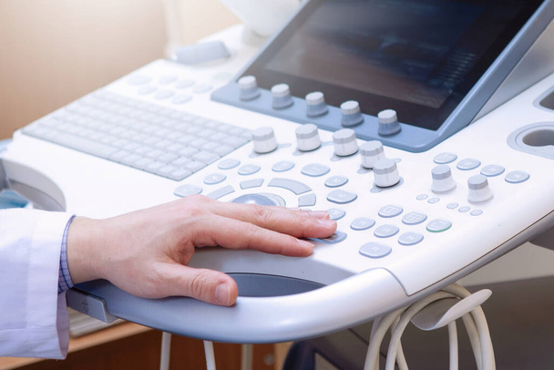Ultrasound examination in a medical clinic. Doctor's hand does a scan. Doctor's hand on the keyboard. - Photo, Image