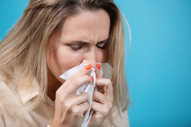 Pandemia koronawirusa. Młoda kobieta kicha i dmucha nos w chusteczkę. Objawy grypy, gorączka, pandemia, epidemia. - Zdjęcie, obraz
