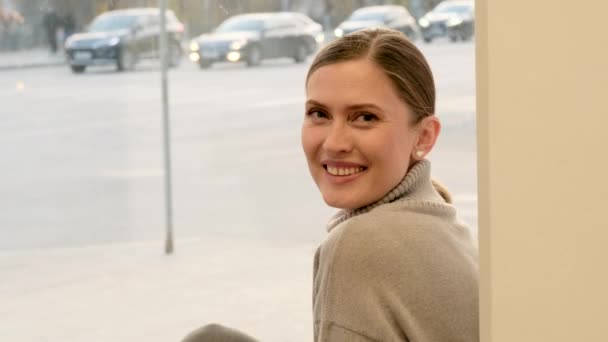 Νεαρή γυναίκα με πουλόβερ ποζάρει για κάμερα κοντά σε μεγάλο παράθυρο - Πλάνα, βίντεο