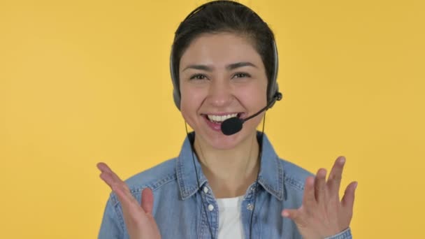 Χαρούμενη νεαρή Ινδή γυναίκα που μιλάει σε ακουστικά, κίτρινο φόντο  - Πλάνα, βίντεο