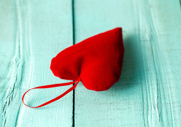 corazón de terciopelo rojo acostado sobre una superficie de madera turquesa, corazón rojo sobre un fondo turquesa - Foto, Imagen