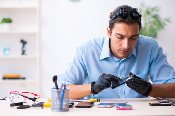 Молодой техник-мужчина ремонтирует мобильный телефон
 - Фото, изображение