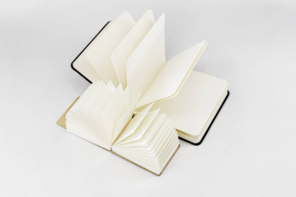 Two fan open small notepads with blank light beige pages. Top view. White background - Zdjęcie, obraz
