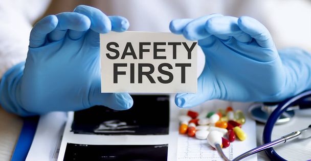 text SAFETY FIRST write on a medicine card. Medical concept with a stethoscope, pills - Foto, afbeelding