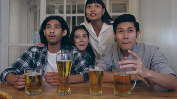 Eine Gruppe junger asiatischer Touristen schaut Fußball im Sportfernsehen, trinkt Alkohol und feiert in einem Nachtclub an der Khao San Road. Reisende Backpacker reisen in Bangkok, Thailand. - Filmmaterial, Video