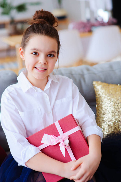 happy kid girl with gift for birthday or christmas posing at home in modern scandinavian interior, preparing or unwraping holiday gift. - Fotó, kép