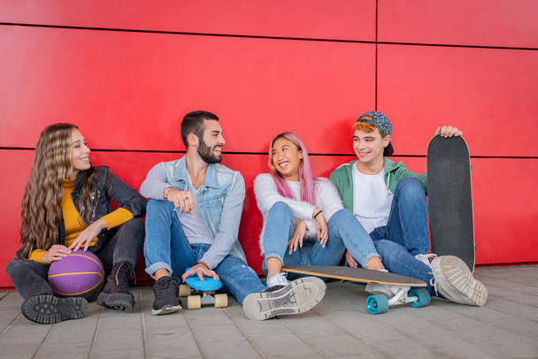 Группа многонациональных друзей, сидящих под открытым небом, смеющихся и смотрящих планшет - Фото, изображение