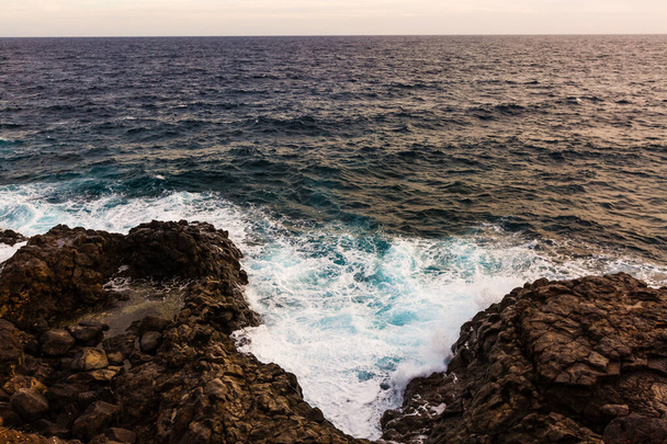 ωκεάνια κύματα χτυπούν και συντρίβονται πάνω σε πέτρες - Φωτογραφία, εικόνα
