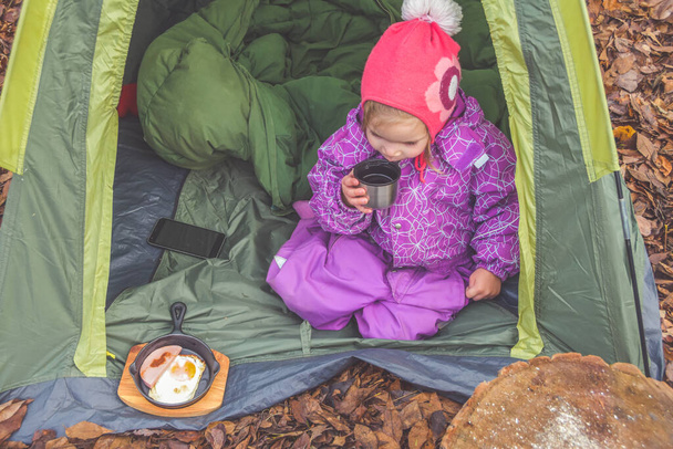 in un giorno d'autunno un bambino sta facendo colazione in una tenda in un campeggio - Foto, immagini