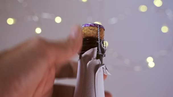 Κοντινό πλάνο στούντιο του ανθρώπου άνοιγμα σαμπάνια με defocused εορταστικά φώτα στο παρασκήνιο - Πλάνα, βίντεο