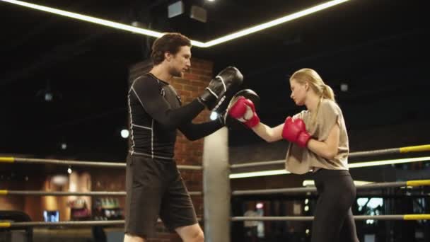 Серьезный боксер-мужчина инструктирует женщину-боксера на боксерском ринге. Спортивная пара в спортзале - Кадры, видео