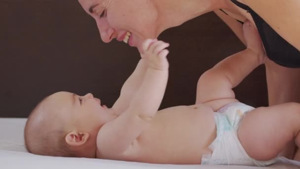 Close-up shot van jonge moeder speelt met haar pasgeboren baby in een kinderkamer in een ochtend. Concept van kinderen, baby, ouderschap, jeugd, leven, moederschap. - Video