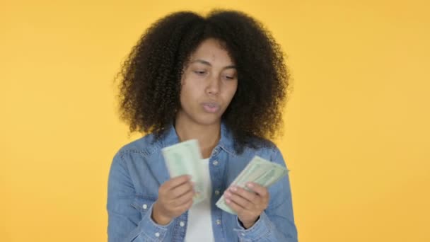 Nuori afrikkalainen nainen laskee dollareita, keltainen tausta  - Materiaali, video