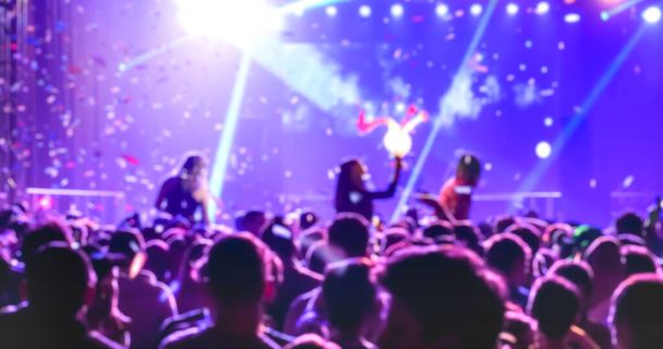 音楽ナイトフェスティバルイベントで踊るぼやけた焦点を当てた人々 -レーザーショーでパーティー後のディスコクラブの抽象イメージの背景-ナイトライフエンターテイメントのコンセプト-コントラストバイオレットフィルター - 写真・画像