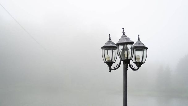 Magányos utcai lámpa a ködben. Szürke és nyirkos kora reggel. Régi vintage utcai fény reggel közelében tó - Fotó, kép