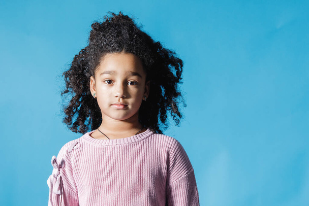 Portret van een Afro-Amerikaans tienermeisje op blauwe achtergrond. Kopieerruimte. - Foto, afbeelding