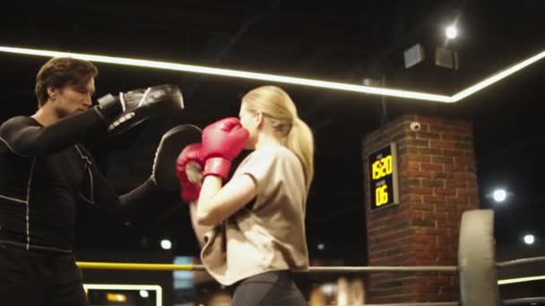 Sport sérieux couple boxe à la salle de gym. Fit girl entraînement avec entraîneur dans le club de sport - Séquence, vidéo