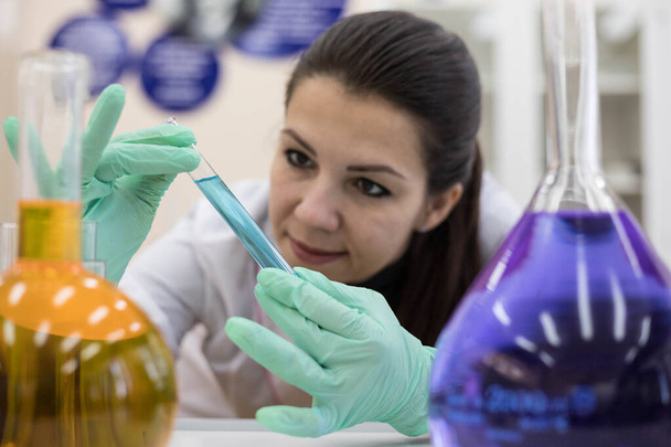 A female chemist examines the contents in a test tube. Work in a modern scientific laboratory. - Photo, image