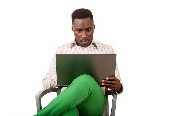 young man sitting in a chair looking at laptop. - Foto, Imagem