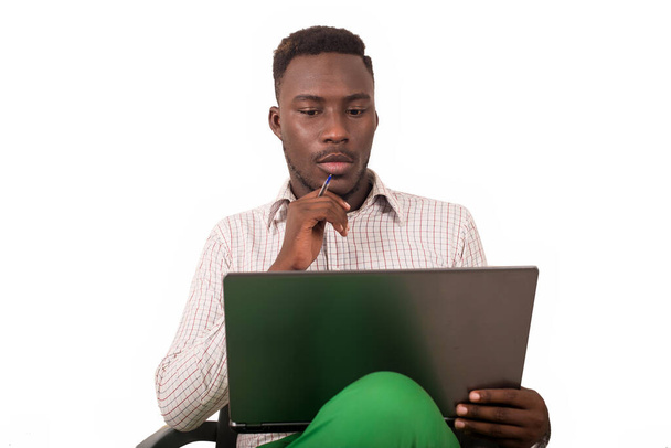 mladý muž sedí v křesle a dívá se na laptop. - Fotografie, Obrázek