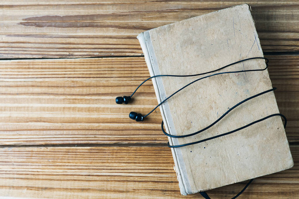 Ses kitapları konsepti. Kopya alanı ile ahşap zemin üzerinde eski kitap ve kulaklık - Fotoğraf, Görsel