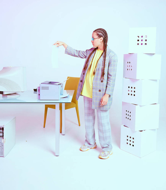 Stylish female worker puts sheet in printer on desk with obsolete computer in office workspace - Zdjęcie, obraz