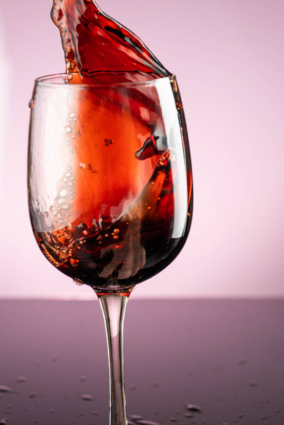splash of red wine in glass on red background - Photo, Image