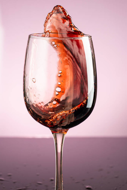 splash of red wine in glass on red background - Foto, Imagem