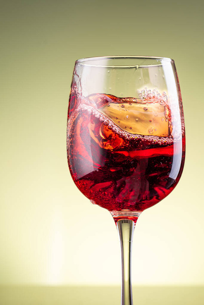 splash of red wine in glass on yellow background - Фото, изображение