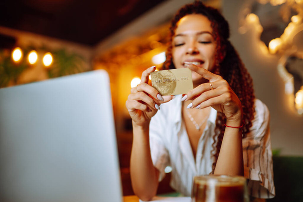Hands holding credit card and using laptop. Young woman doing online shopping sitting at cafe. Online shopping, e-commerce, internet banking, spending money. Purchases, black friday, discounts, sale. - Foto, afbeelding
