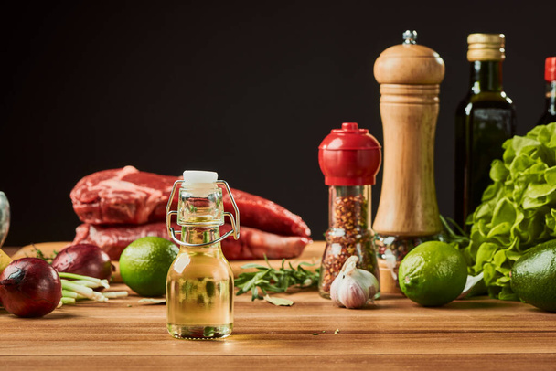 Small bottle of seed oil in front of other ingredients on wooden table - 写真・画像