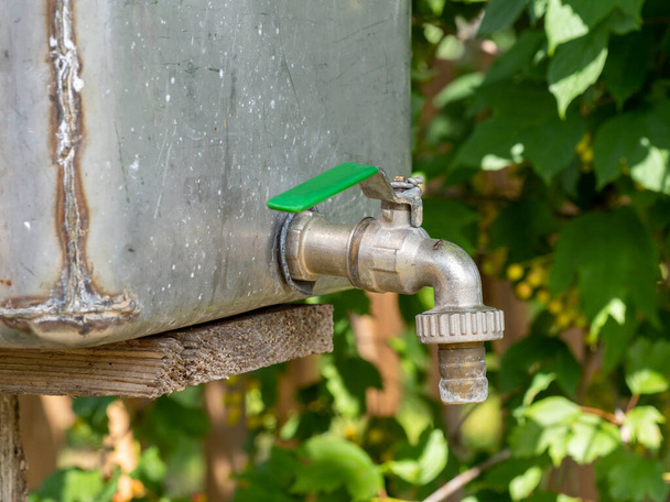 rubinetto dell'acqua aperta o rubinetto con acqua corrente in fondo al giardino sfocato - Foto, immagini