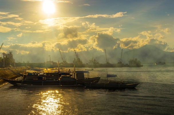 Величний вечірній краєвид на Пуерто-Прінсеса на острові Палаван, Філіппіни. Золоті яскраві промені сонця на морі. Традиційні філіппінські човни пришвартовані біля вантажного порту. - Фото, зображення