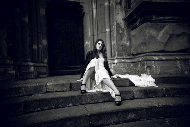 Foto de mujer en vestido largo sentada en escaleras de piedra en el castillo
 - Foto, Imagen