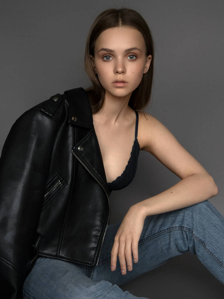 Krásná modelka. Model test portrét s mladou krásnou módní model pózovat na šedém pozadí. Nosí podprsenku a džíny. - Fotografie, Obrázek