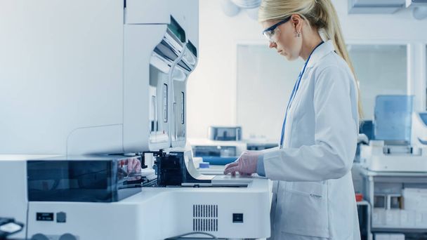 Female Research Scientist Putting Test Tubes with Blood Samples into Analyzer Medical Machine. Scientist Works with Modern Medical Equipment in Pharmaceutical Laboratory. - Foto, Bild