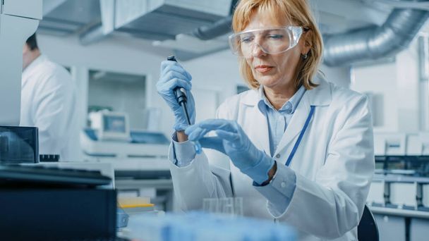 Female Research Scientist Uses Micro Pipette while Working with Test Tubes. People in Innovative Pharmaceutical Laboratory with Modern Medical Equipment for Genetics Research. - 写真・画像