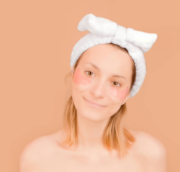 Young girl with patches under the eyes on a beige background - Photo, Image