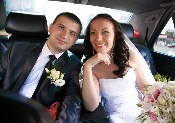 Супружеская пара, сидящая на заднем сидении машины и смотрящая в камеру
 - Фото, изображение