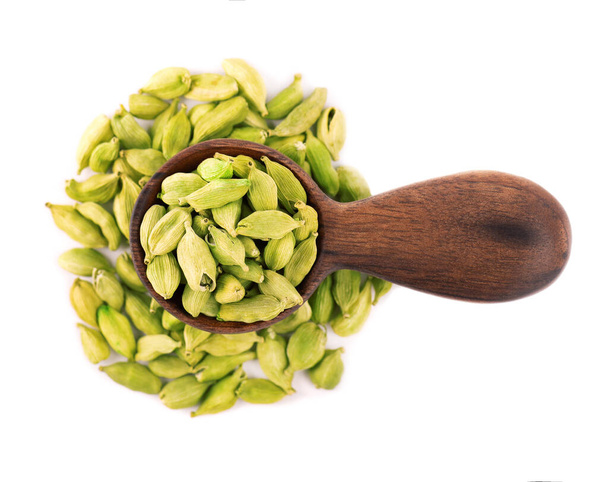 Cardamom seeds in wooden spoon, isolated on white background. Pile of green cardamom pods. Top view - Photo, Image