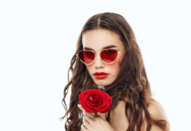 Обрізаний вид сексуальної брюнетки в окулярах з червоною квіткою в руках
 - Фото, зображення