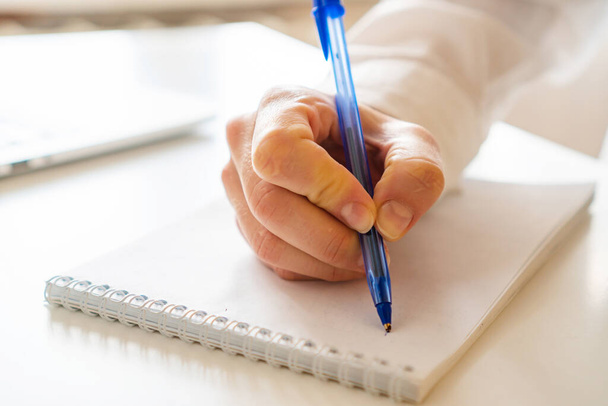 γυναικείο χέρι κρατά σημειώσεις με ένα στυλό σε ένα σημειωματάριο - Φωτογραφία, εικόνα