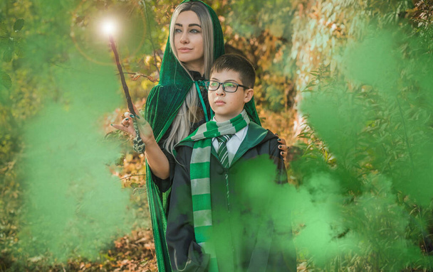 Παιδί και μάγισσα μέσα στη μαγική ατμόσφαιρα. Αγόρι και μαμά με πράσινη ρόμπα μαγεία στο δάσος. Οικογένεια Απόκριες - Φωτογραφία, εικόνα