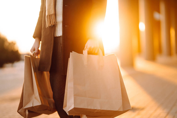 Hand of young man with paper bags with purchases at sunset. Purchases, black friday, discounts, sale concept. Autumn shopping. - Fotografie, Obrázek