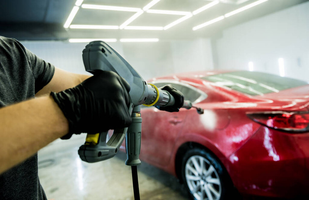 Worker washing car with high pressure water at a car wash. - Foto, Imagem