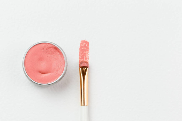Un trazo de lápiz labial teñido vegano desnudo rosa o rubor de mejilla en un papel blanco. Producto Zero Waste en envases metálicos recargables y ecológicos. Copiar espacio para texto - Foto, imagen